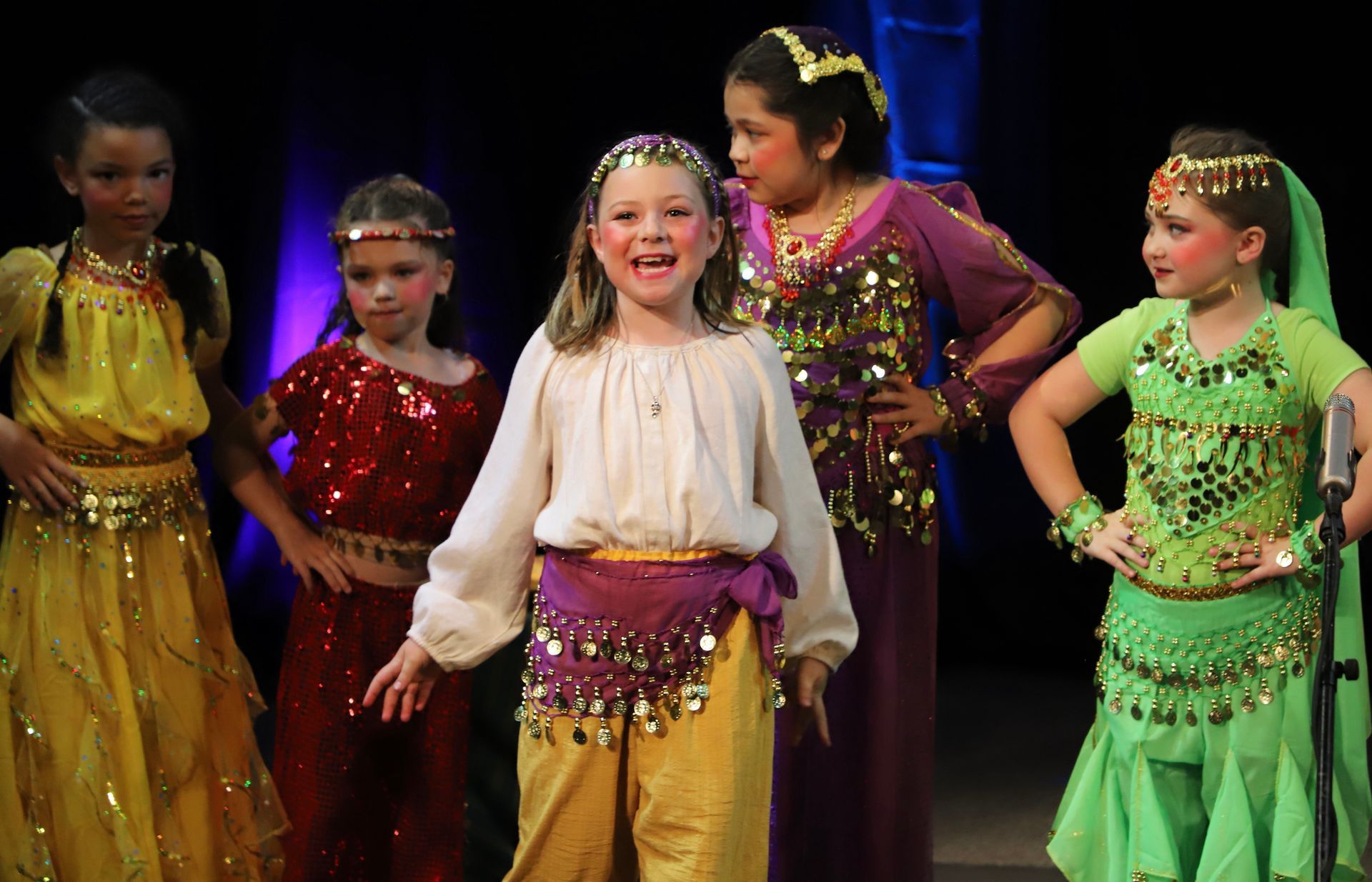 A group of young girls dressed in oriental costumes are standing on a stage.