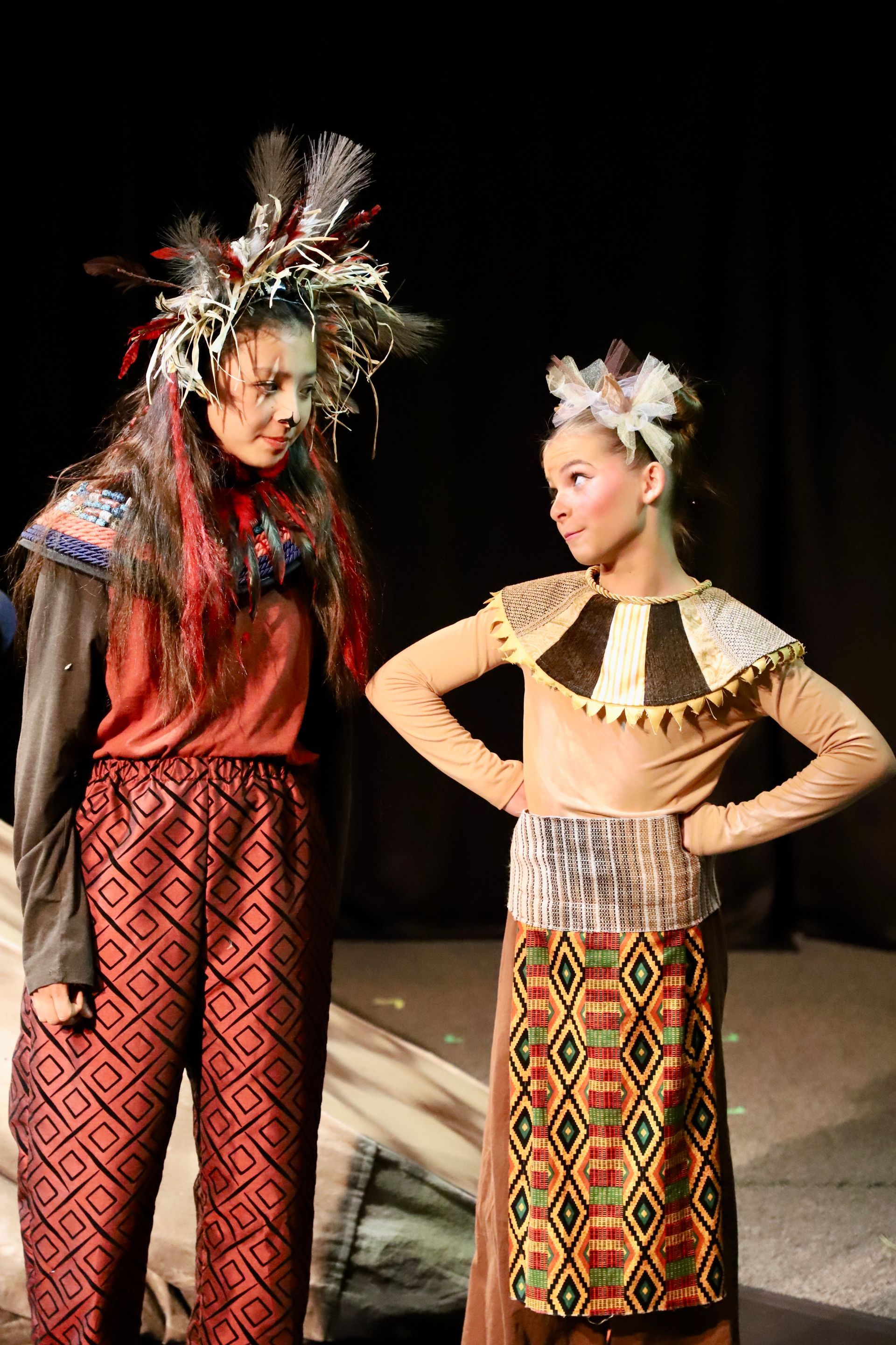 Two women in native american costumes are standing next to each other on a stage.