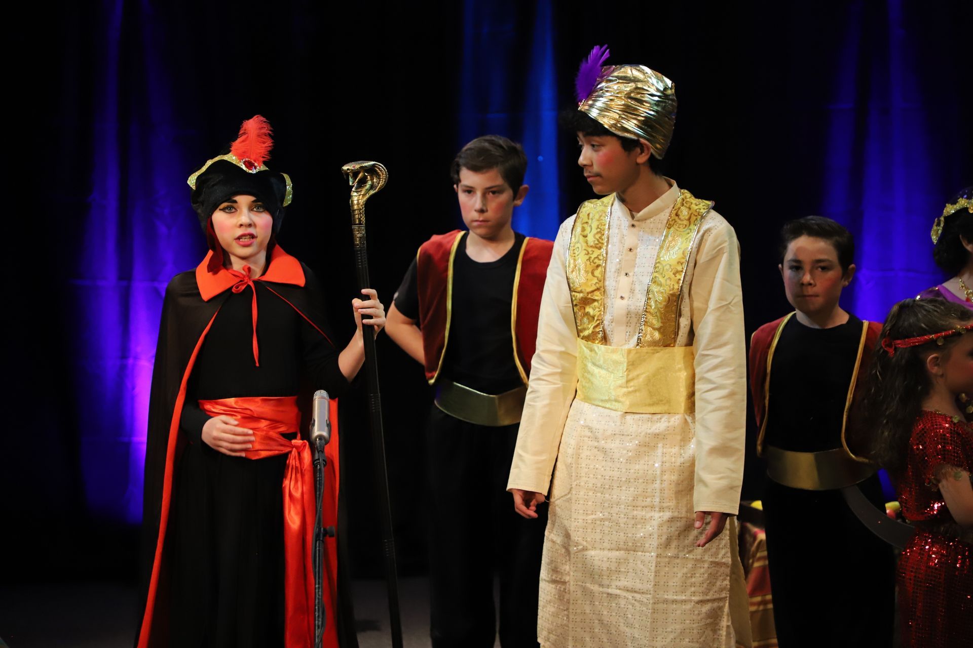 A group of children dressed in costumes are standing on a stage.