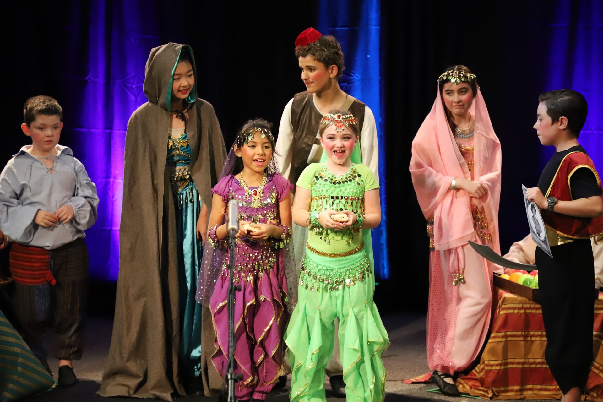 A group of children dressed in costumes are standing on a stage.