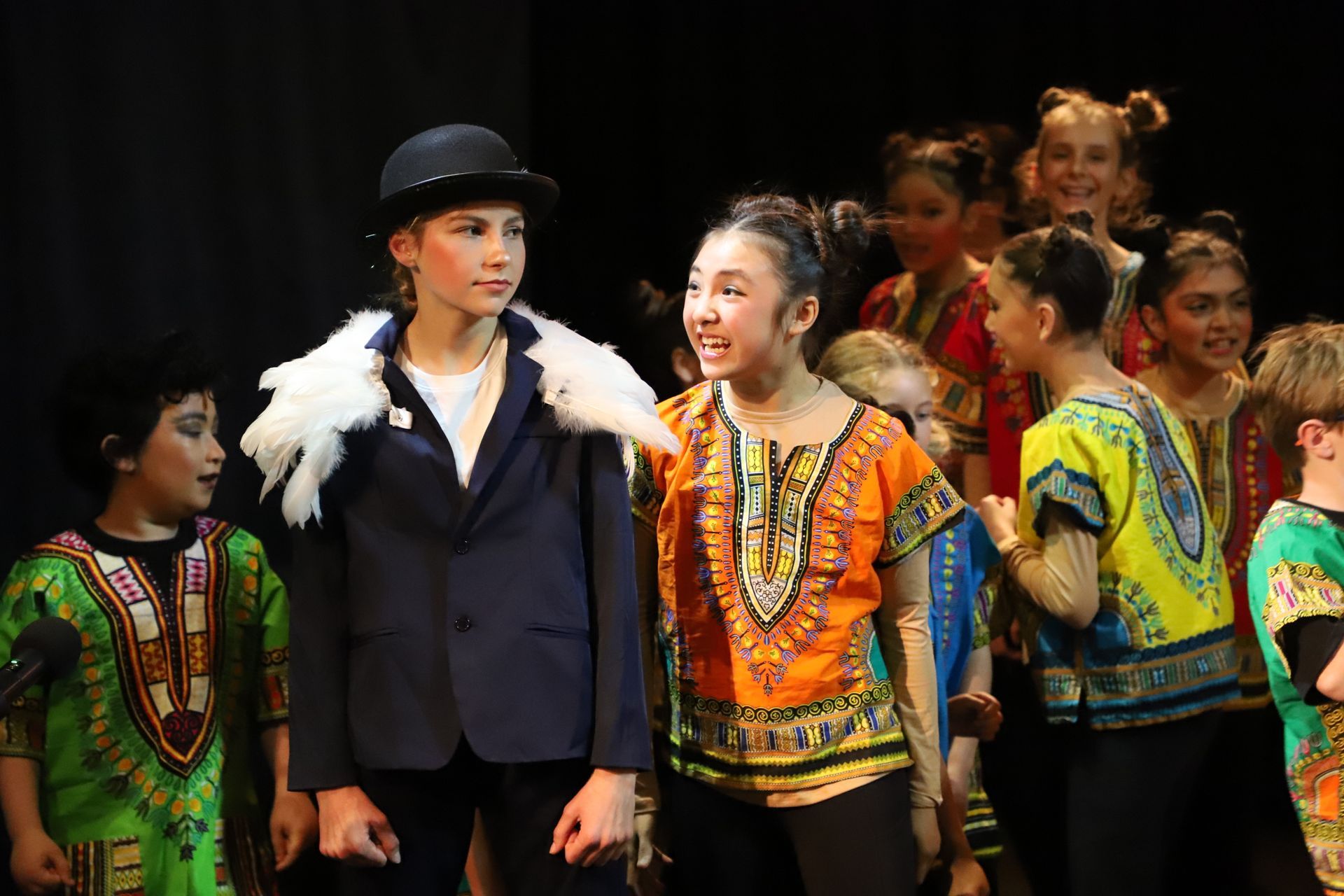 A group of children are standing next to each other on a stage.