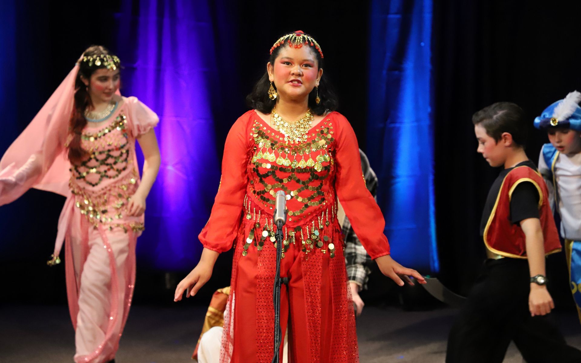 A woman in a red dress is standing in front of a microphone on a stage.