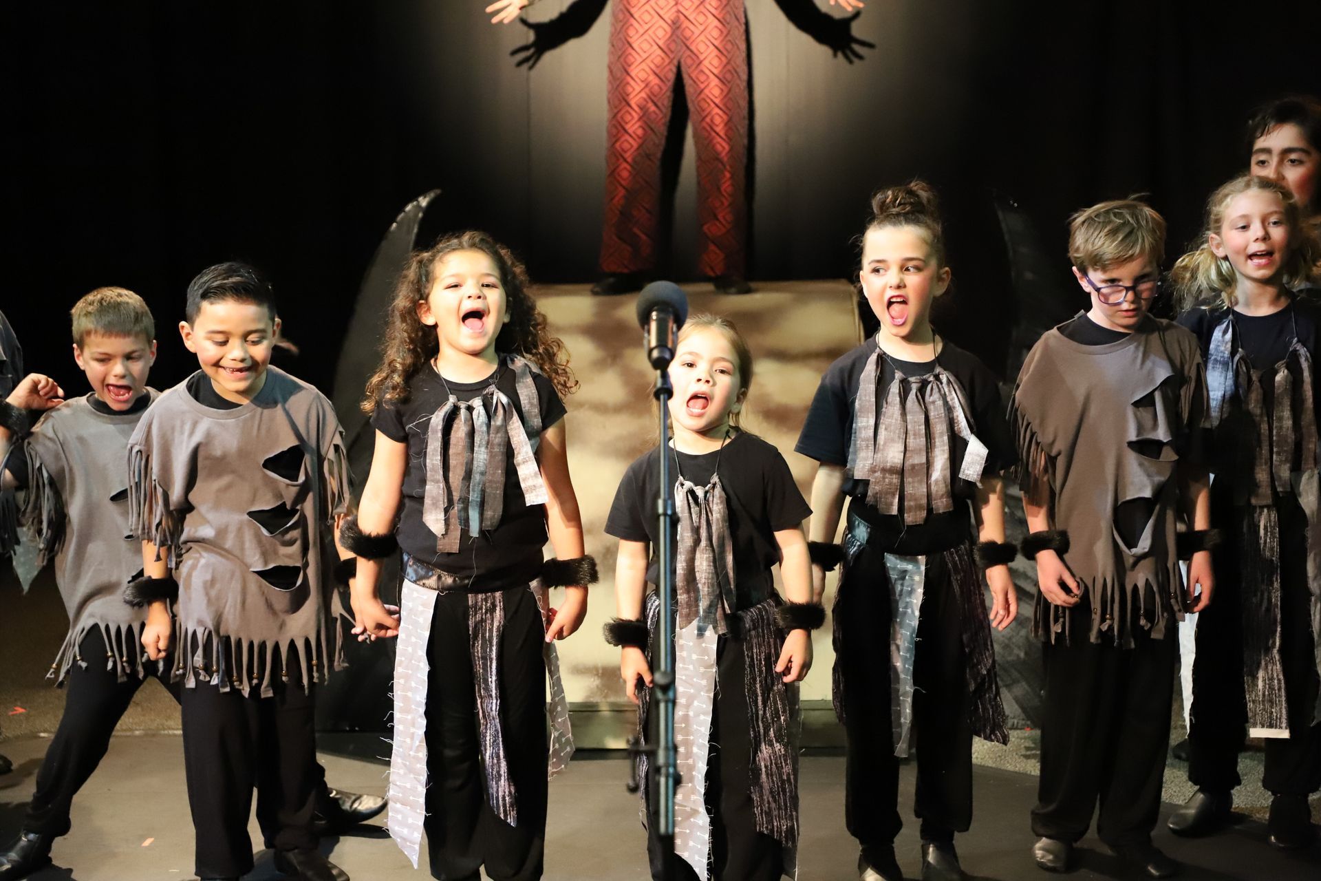A group of children are singing into microphones on a stage.