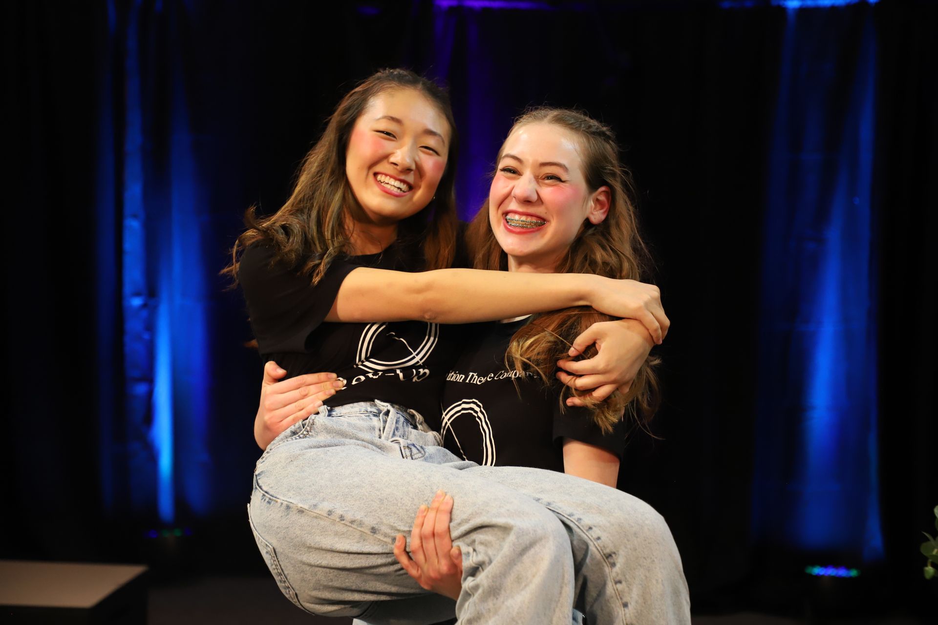 A woman is carrying another woman in her arms on a stage.