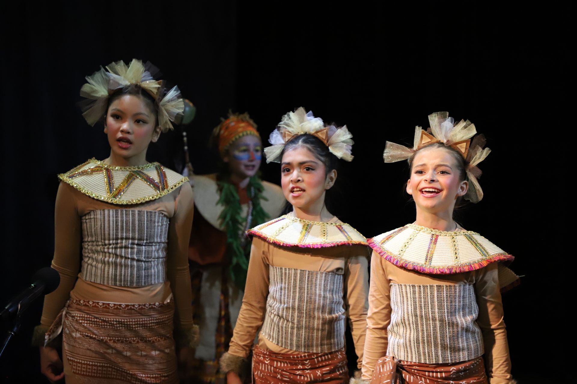 A group of young girls in costume are standing next to each other on a stage.