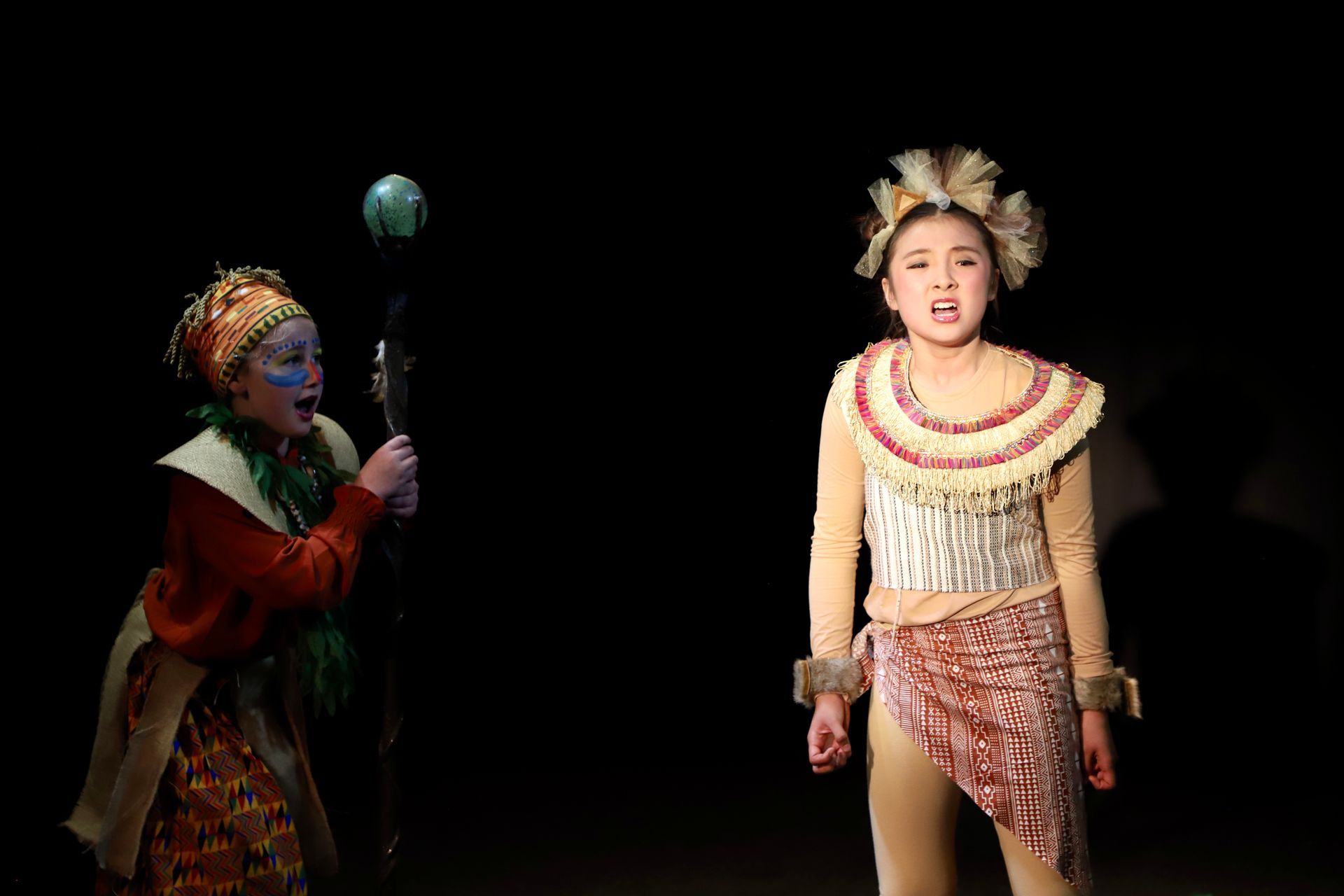 A woman in a costume is standing next to another woman in a costume on a stage.