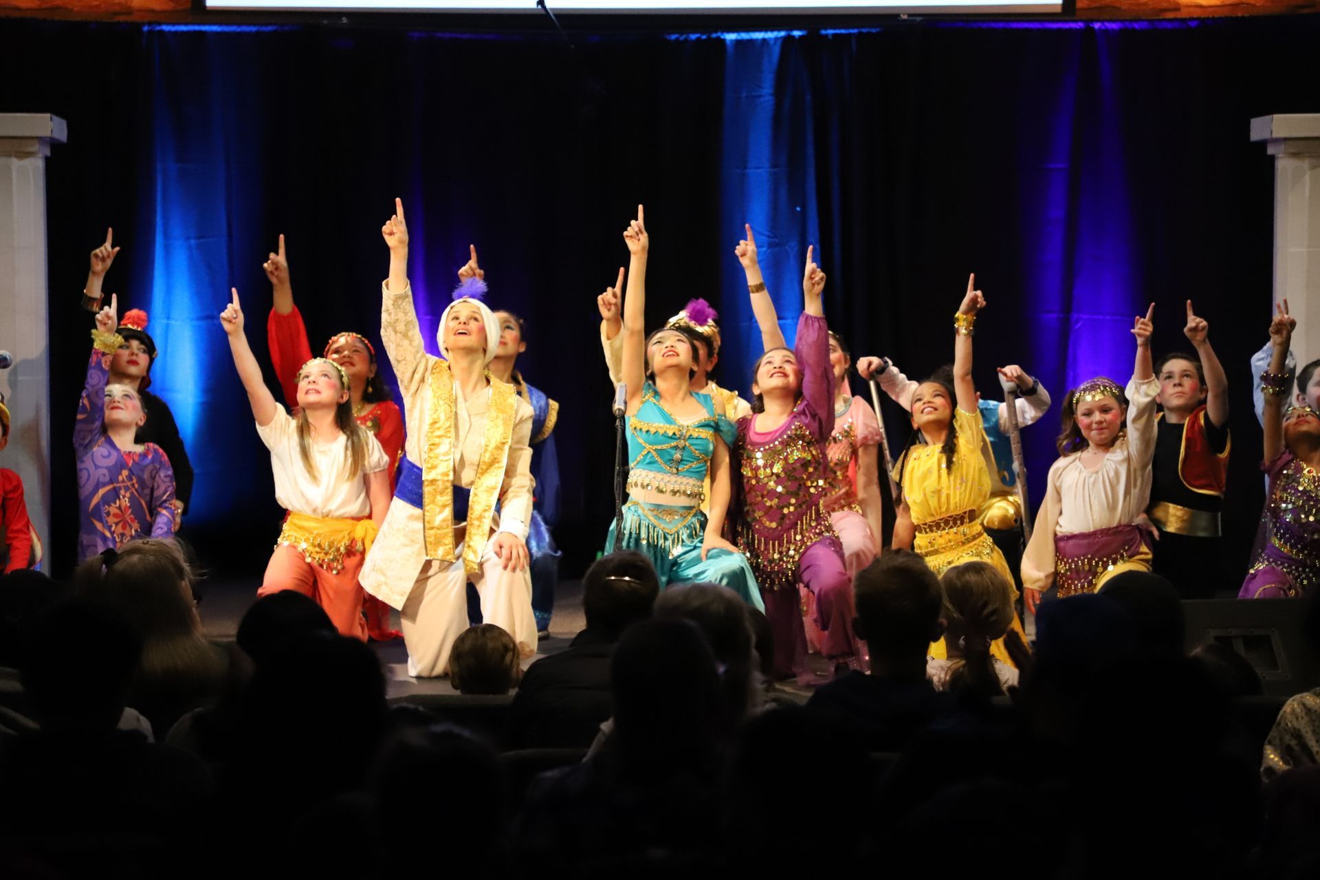 A group of people are dancing on a stage in front of a crowd.