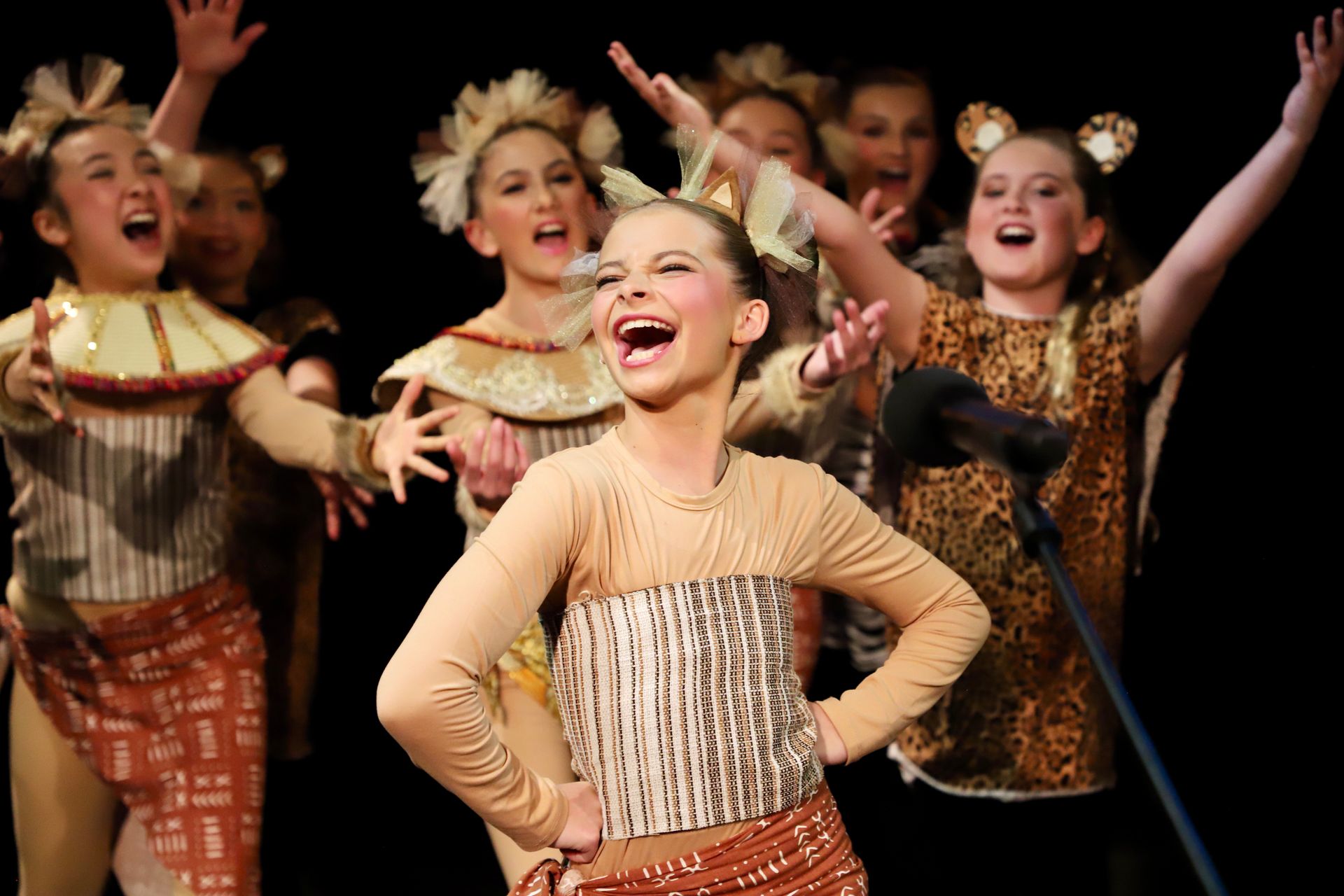 A group of young girls are performing on stage and one girl is laughing