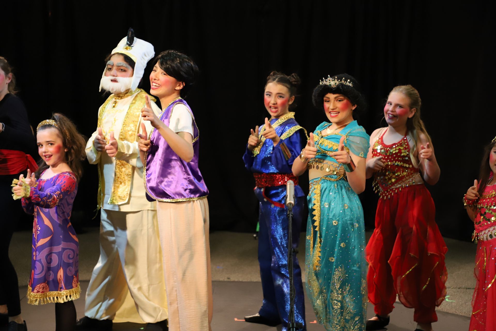 A group of children dressed in costumes are standing on a stage.