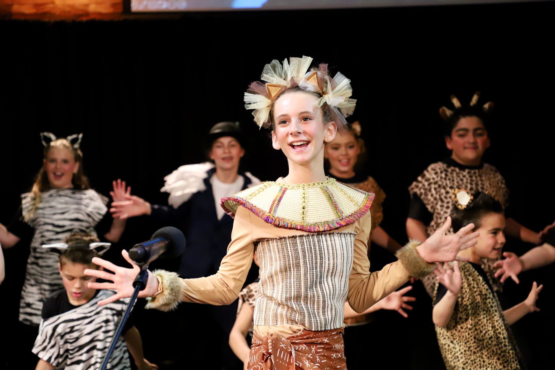 A group of children dressed in costumes are dancing on a stage.
