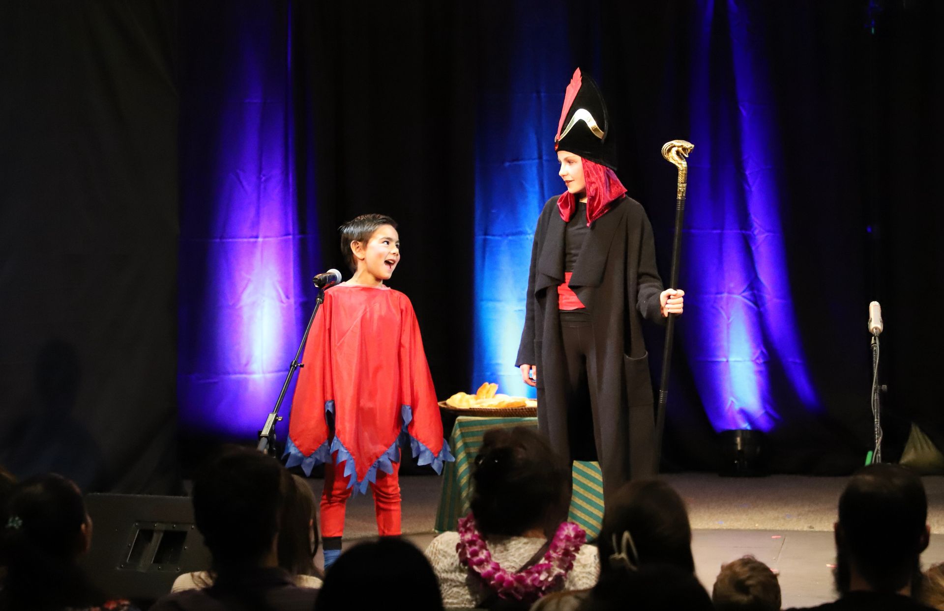 A man and a boy are standing on a stage in front of a crowd.