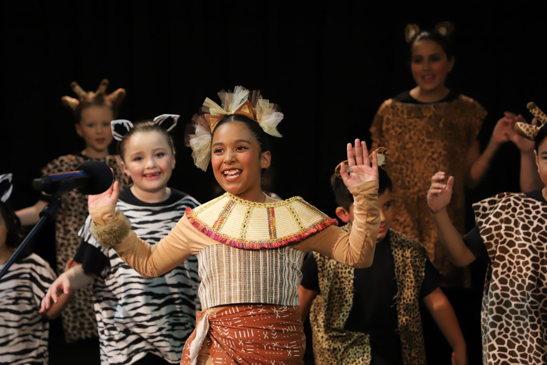 A group of children in costume are dancing on a stage.