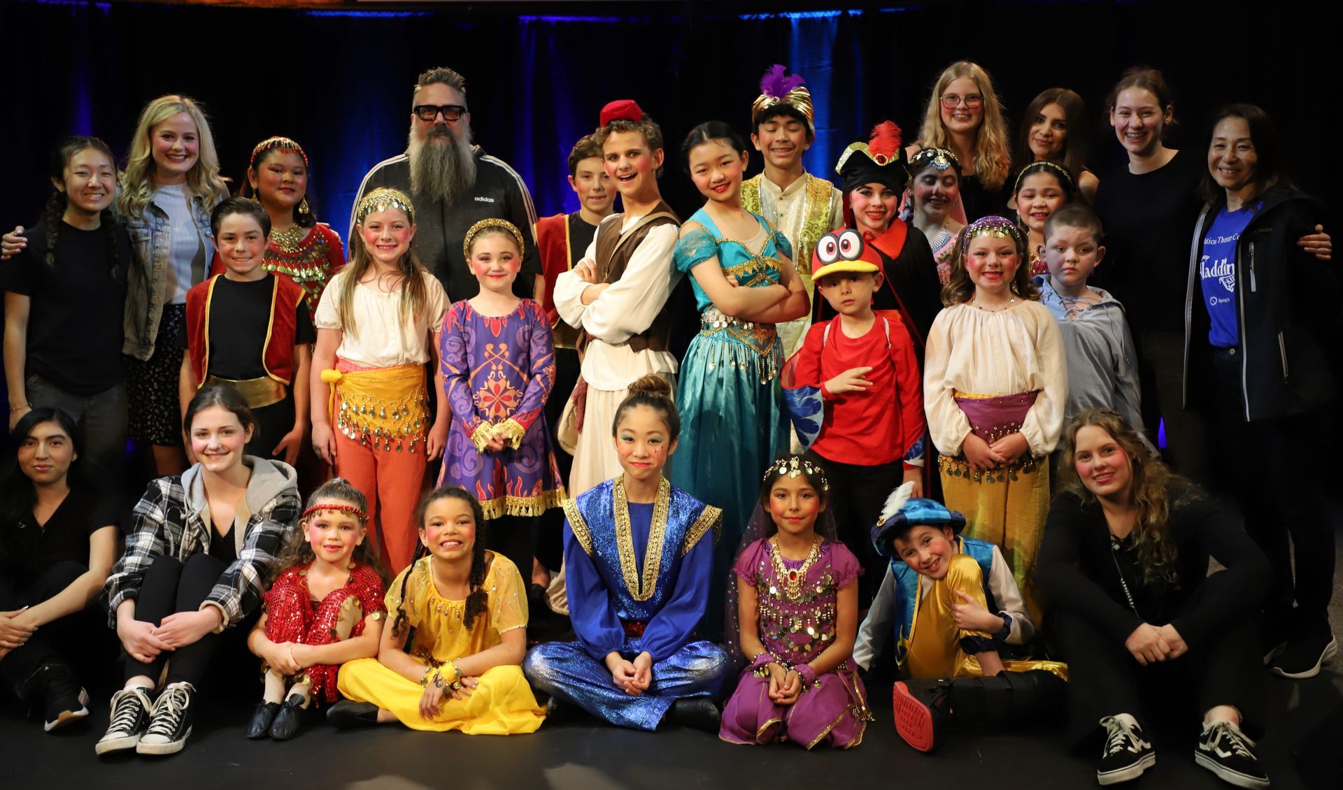 A group of people in costumes are posing for a picture on a stage.