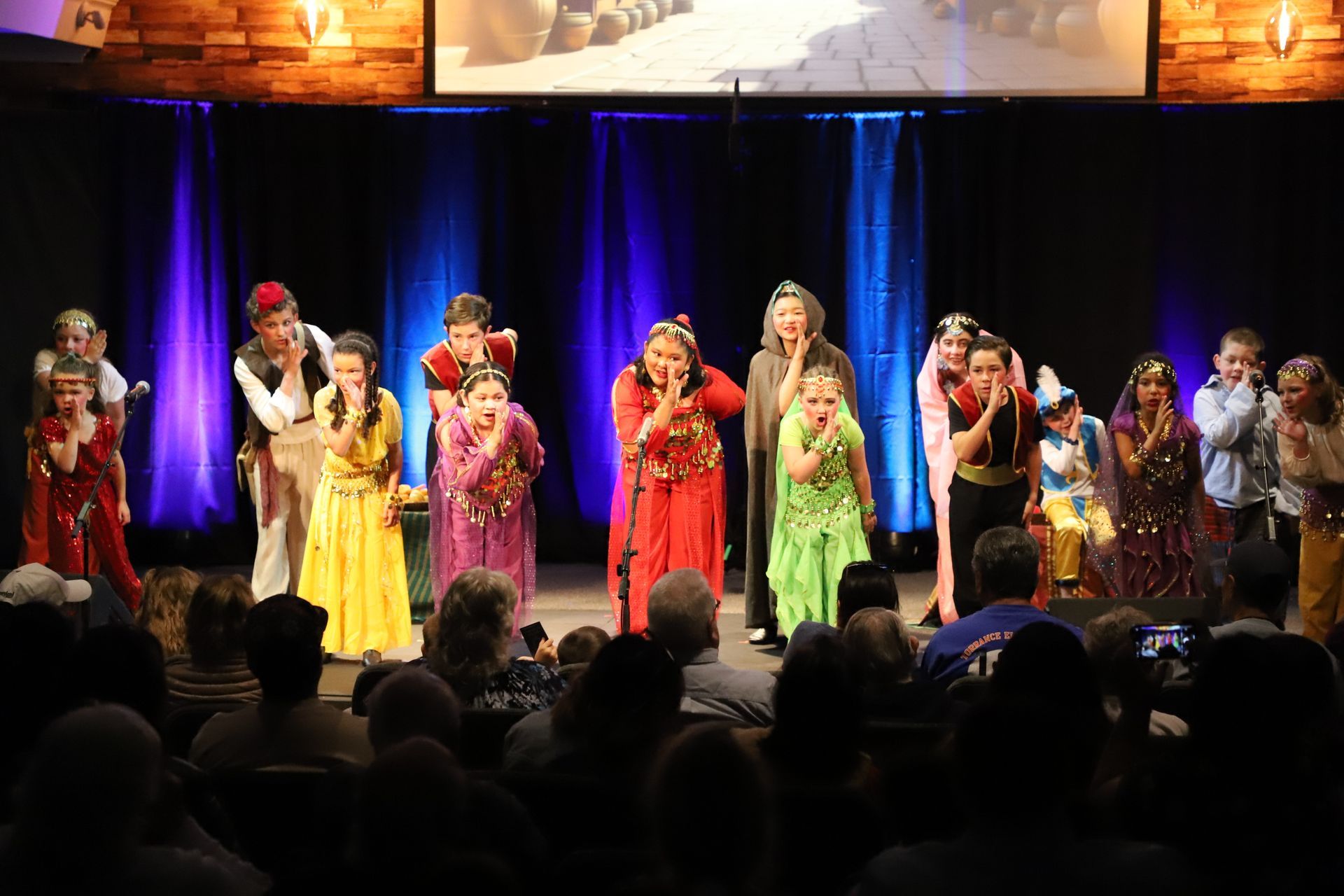 A group of people are standing on a stage singing into microphones.