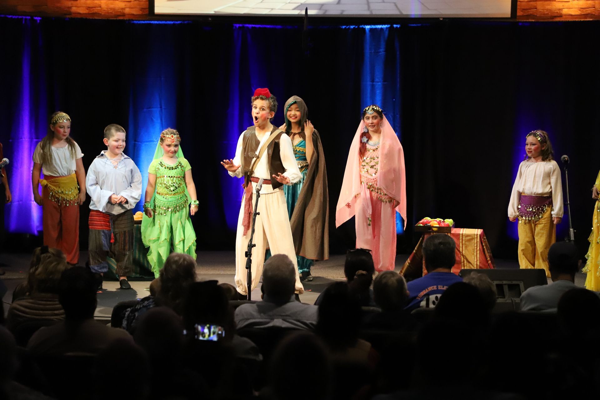 A group of people are standing on a stage in front of a crowd.