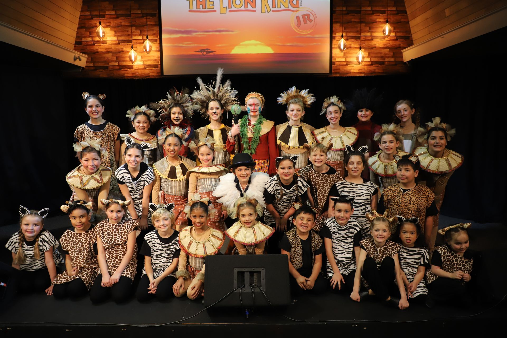 A group of children are posing for a picture in front of a screen that says the lion king