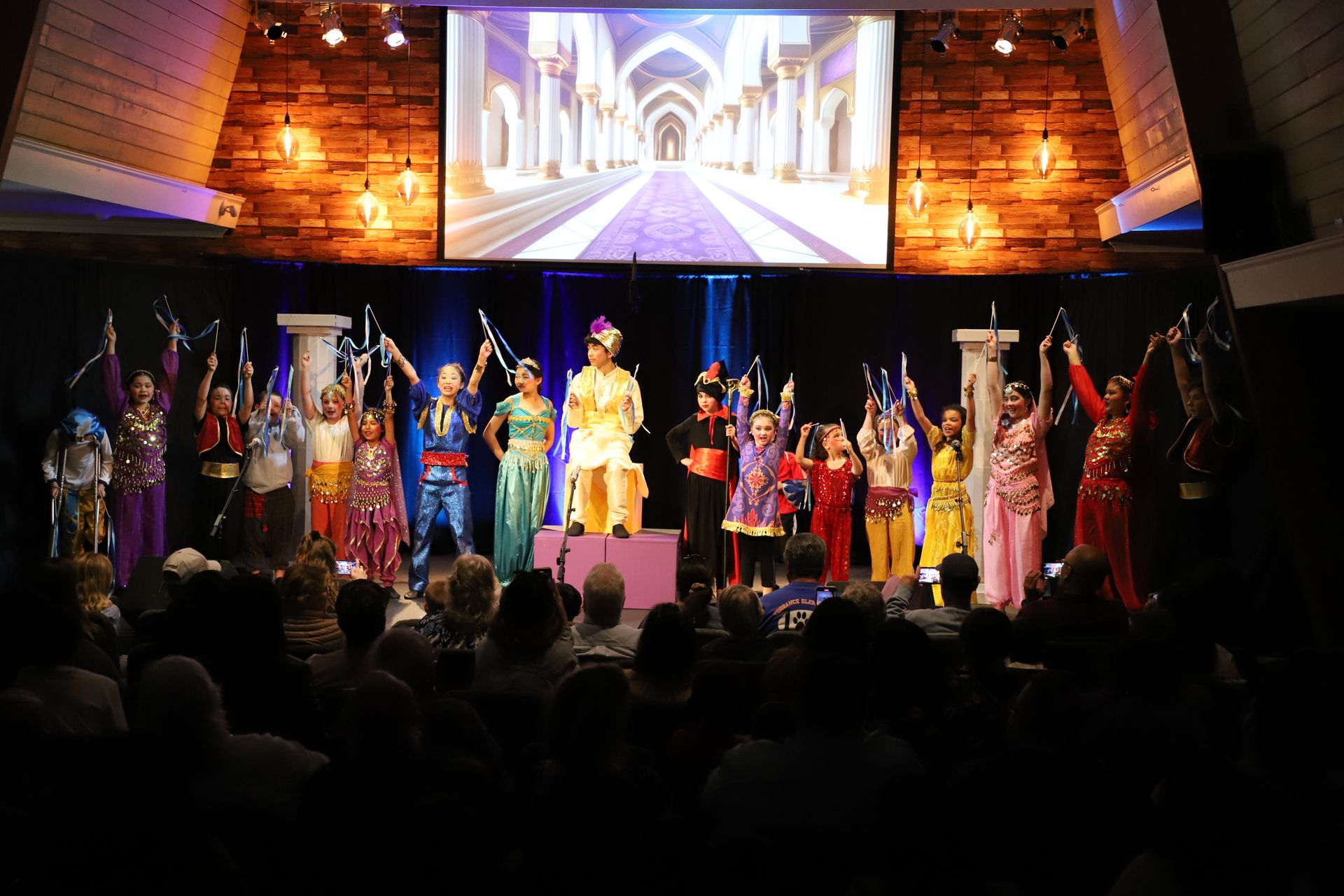 A group of people are standing on a stage in front of a large screen.