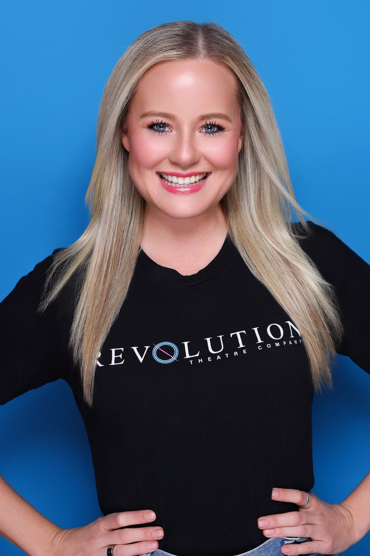 A woman with blonde hair and blue eyes is wearing a purple top