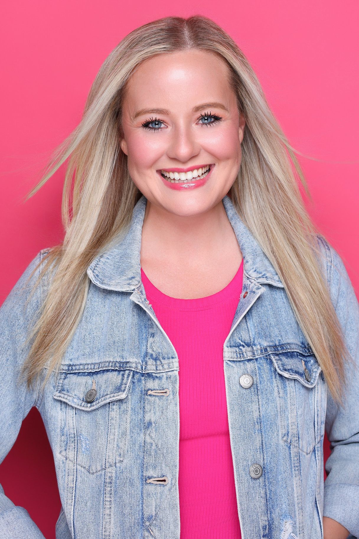 A woman with blonde hair and blue eyes is wearing a purple top