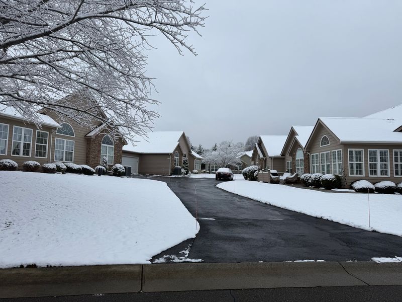 Snow-covered suburban street with houses and driveways after fresh snowfall