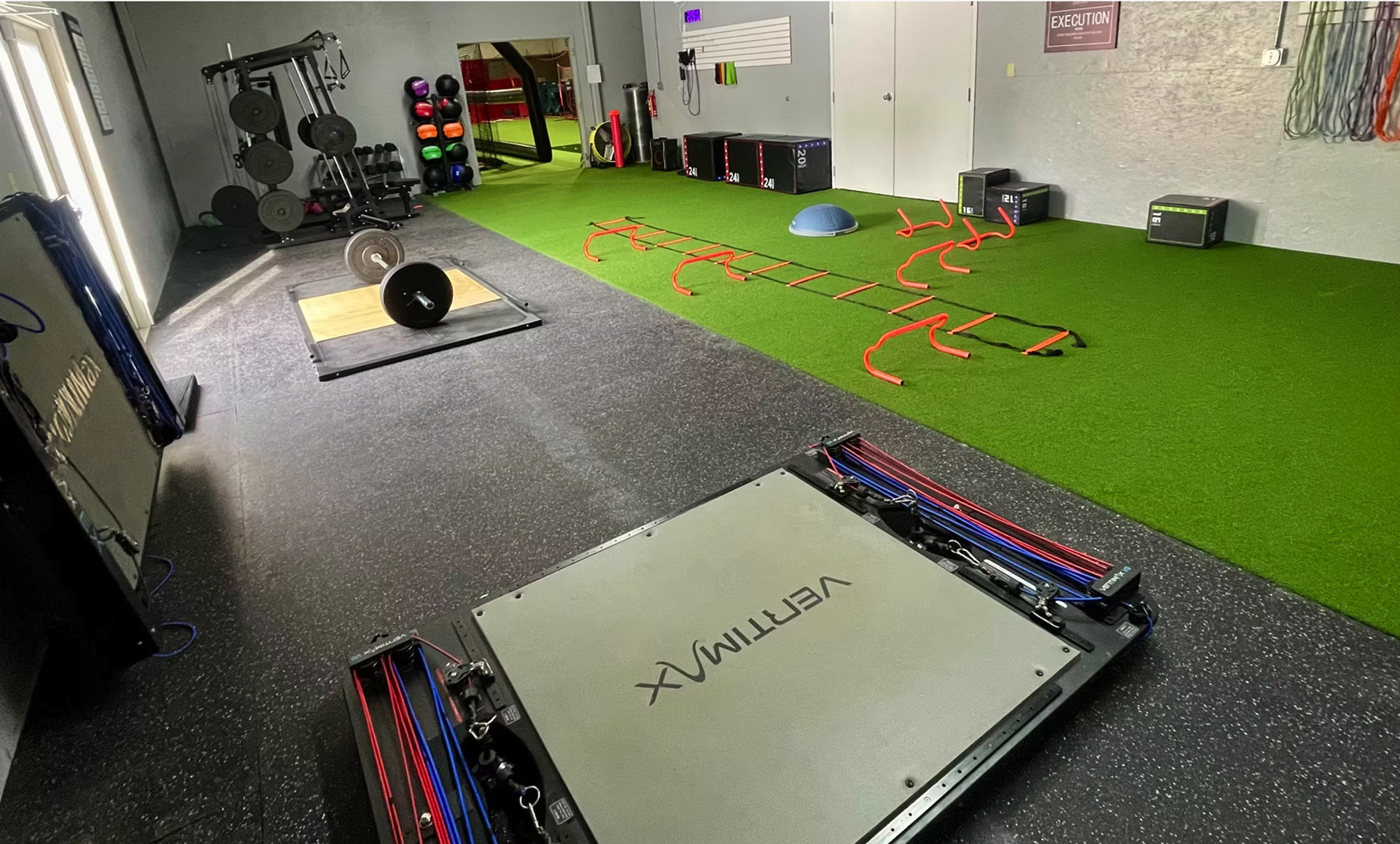 A gym with a lot of equipment on the floor and a white box on the floor.