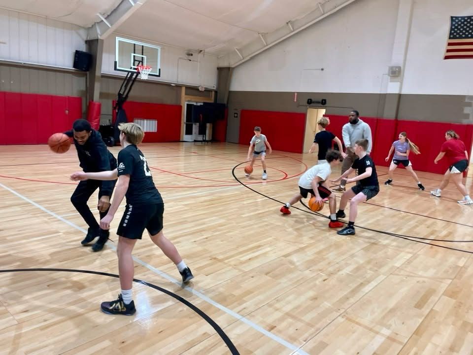A group of children are playing basketball in a gym.