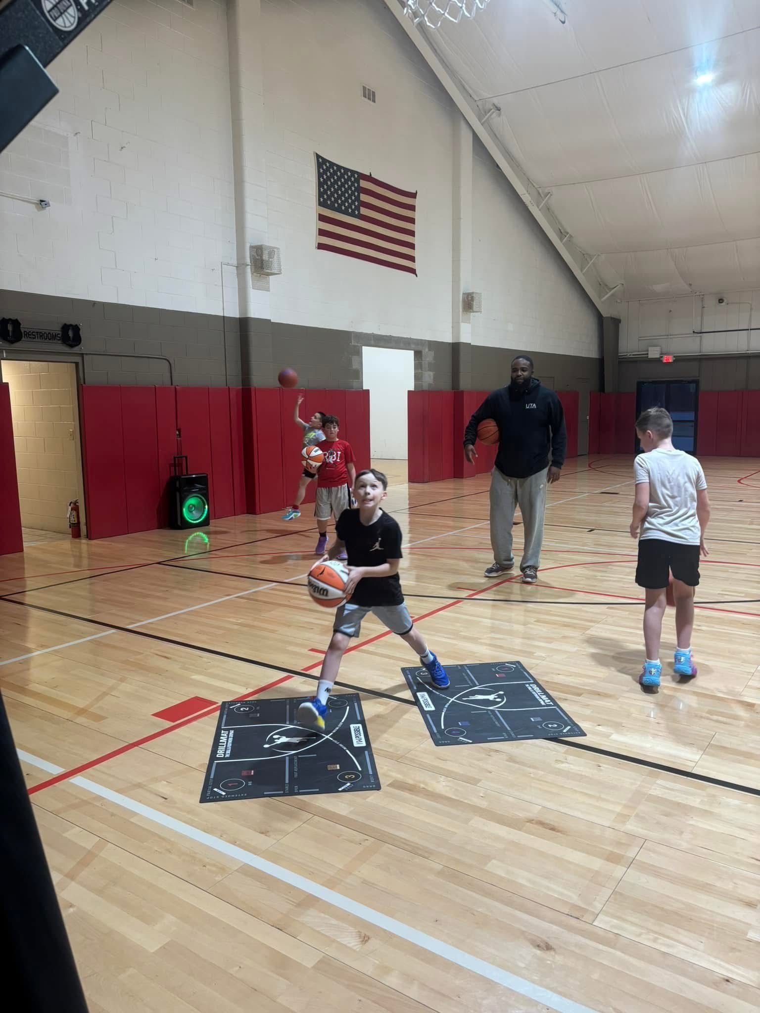 A group of children are playing basketball in a gym.