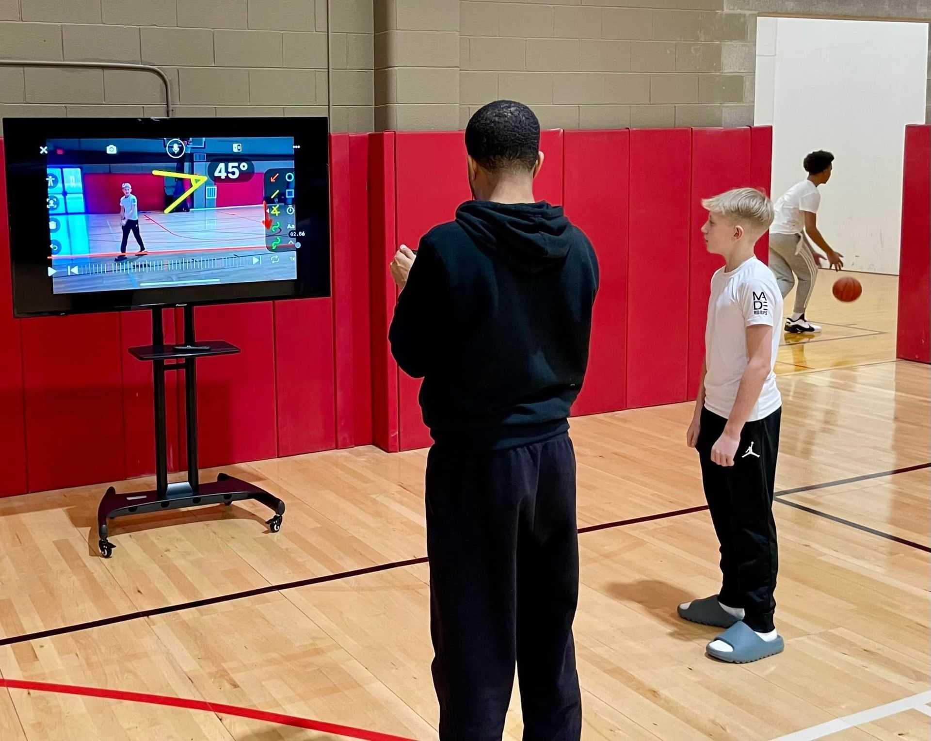 A man and a boy are playing a video game in a gym.