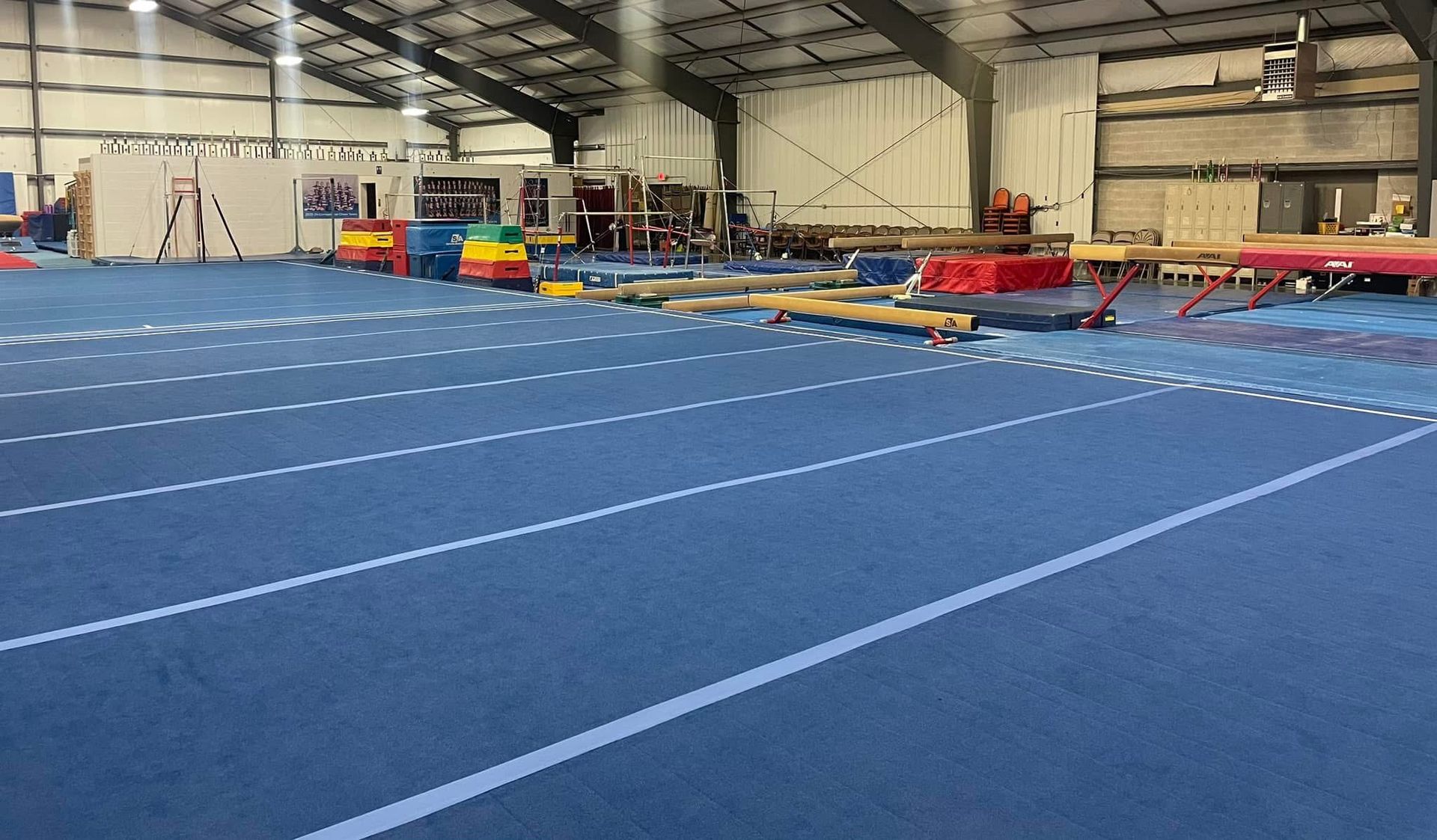A large indoor gym with a blue carpet and a lot of equipment.