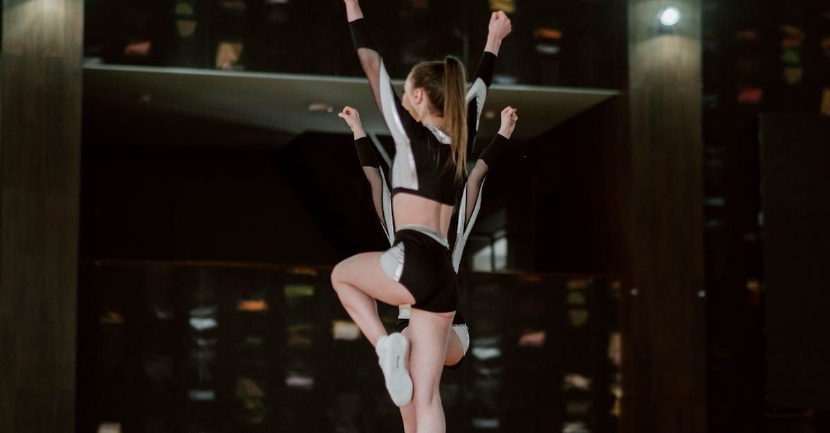 A cheerleader is standing on one leg in front of a mirror.
