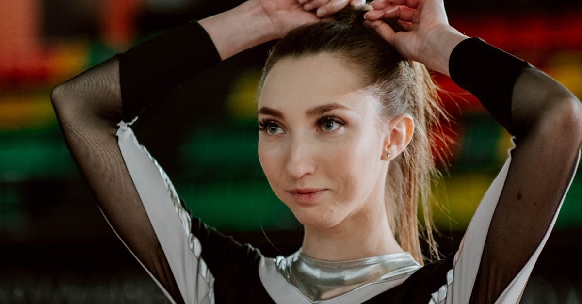 A female gymnast is tying her hair in a ponytail.