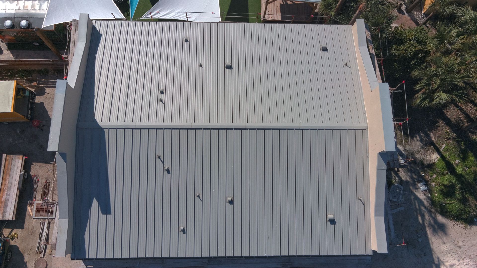 Overhead view of a building with a metal roof. The roof has corrugated metal and ventilation holes.