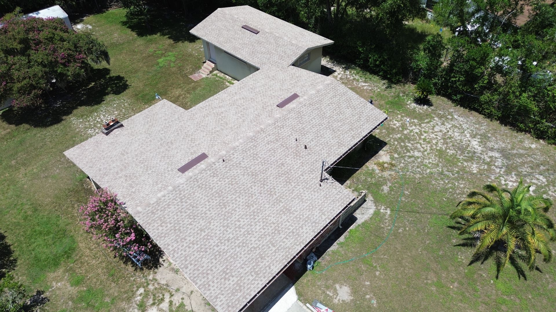 Aerial view of a house and shed with gray roofs and green lawn.