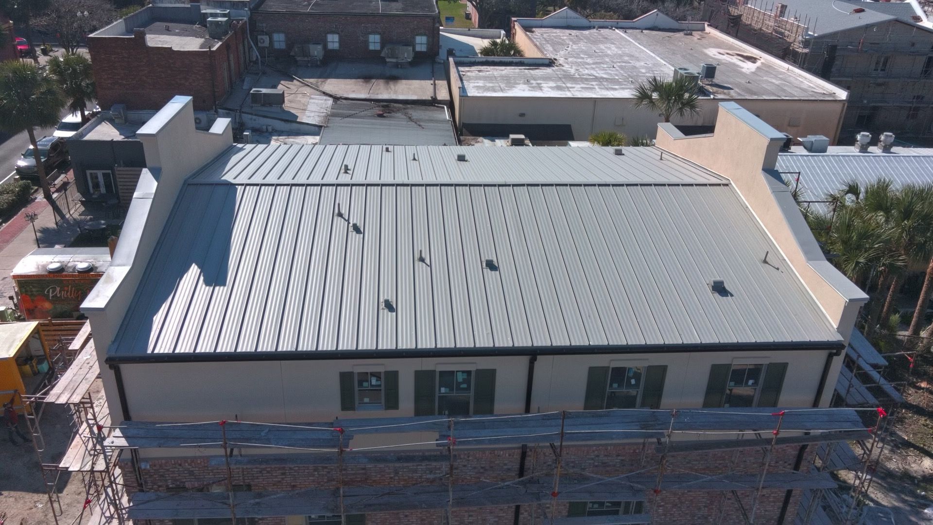 An aerial view of a building with a metal roof. Scaffolding is on the front.
