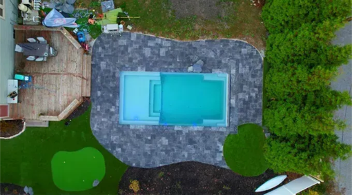 Lush green lawn with a stone pathway lined by trees with autumn leaves.