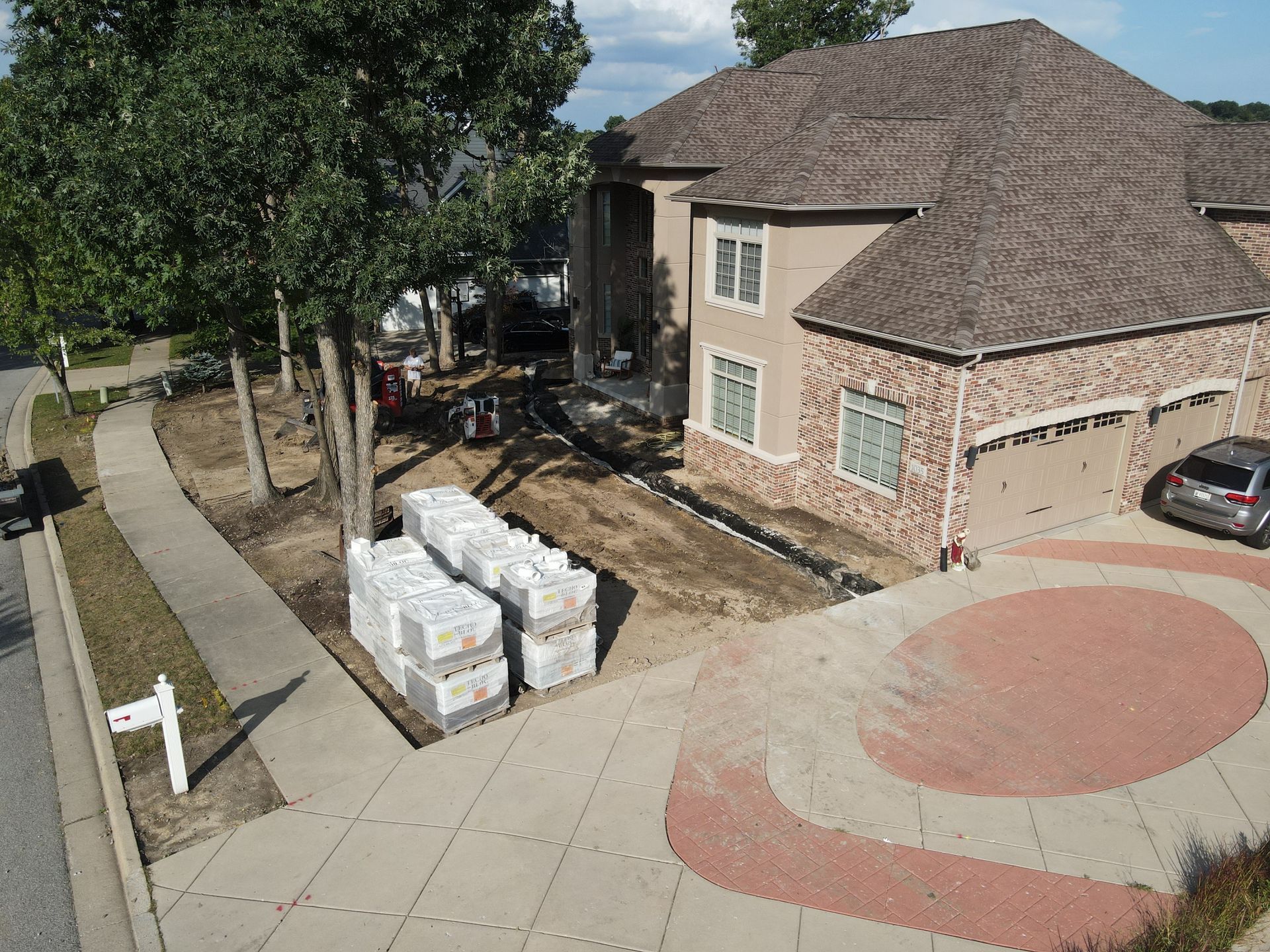 A house under construction with building materials in front and a driveway.