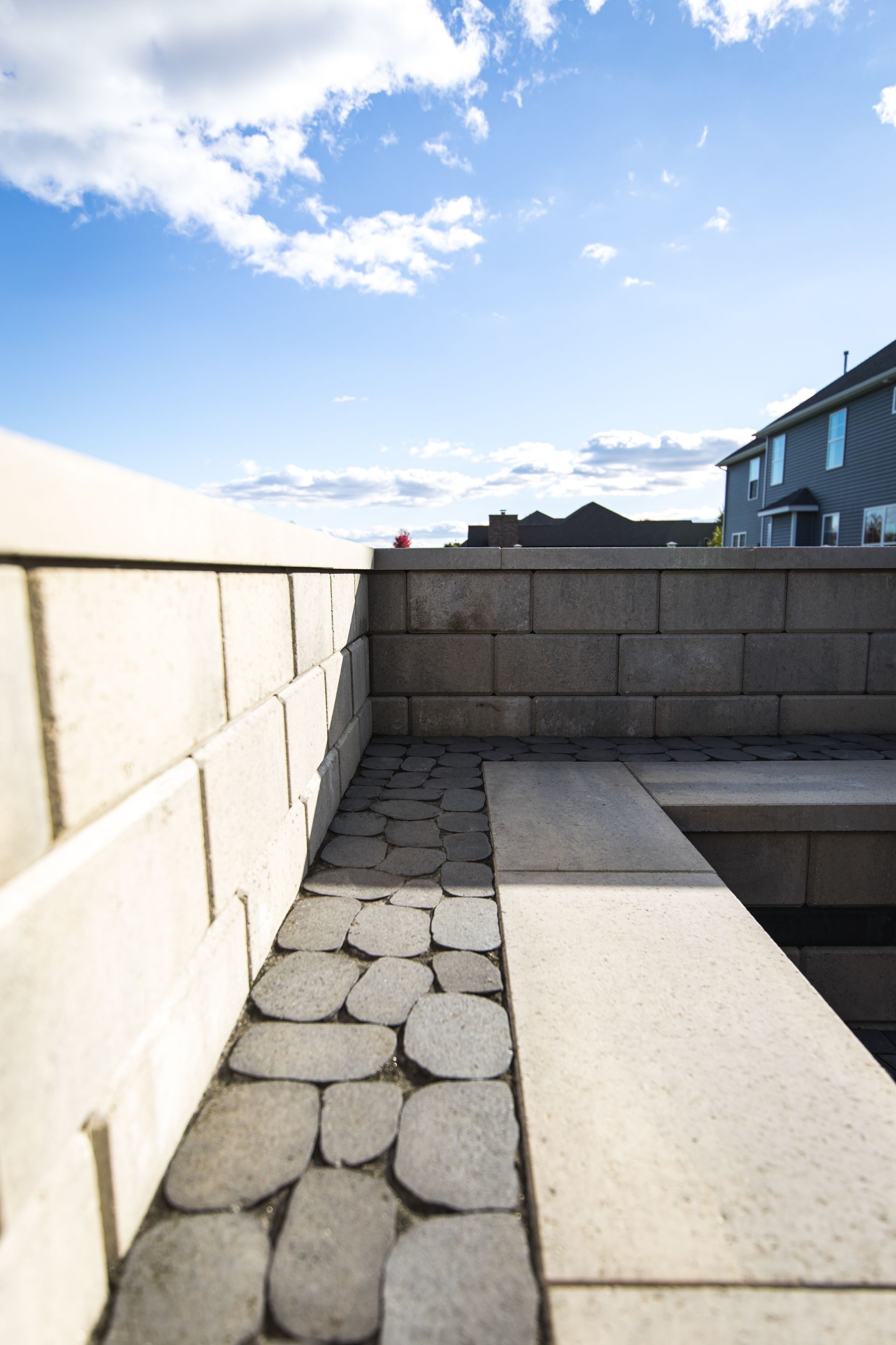 Stone patio with brick wall and blue sky.