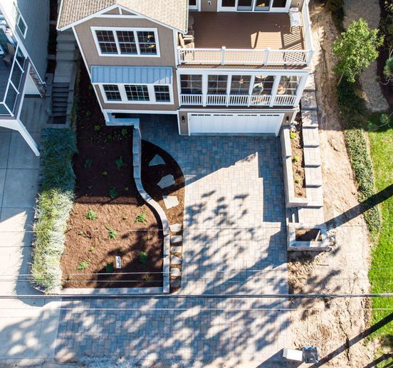 Overhead view of a two-story home with a garage, driveway, and landscaping.