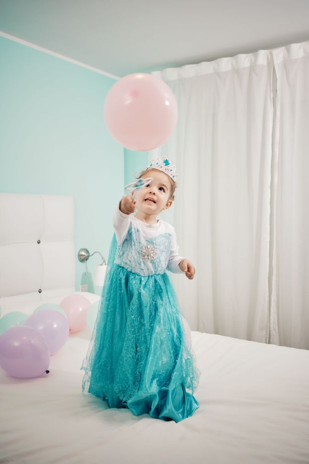Una bambina vestita da Elsa di Frozen tiene in mano un palloncino rosa.