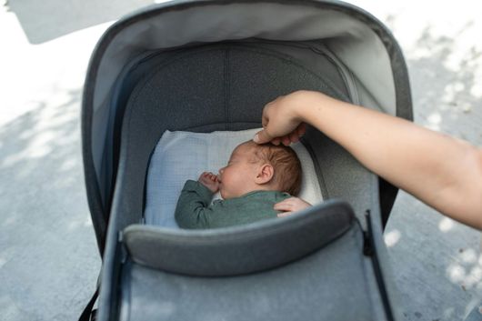 Una donna sta mettendo un bambino nel passeggino.