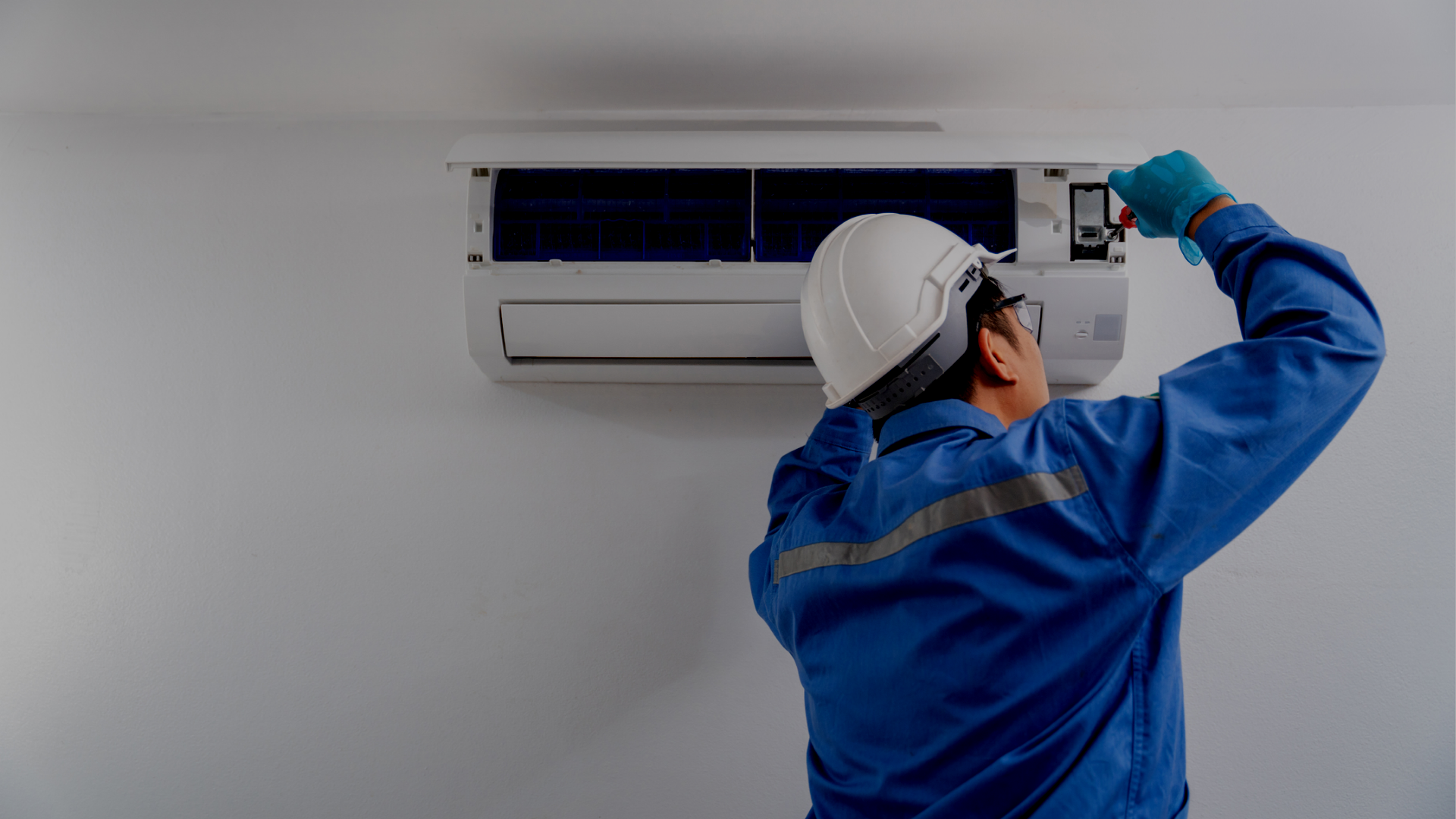 A man is working on an air conditioner in a room.
