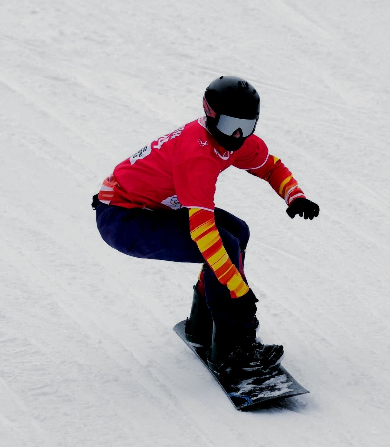 Un snowboarder con casco y gafas desciende por una pendiente nevada