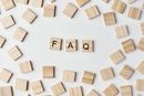 The letters F, A, and Q on wooden tiles centered among many scattered, blank wooden tiles on a white background.