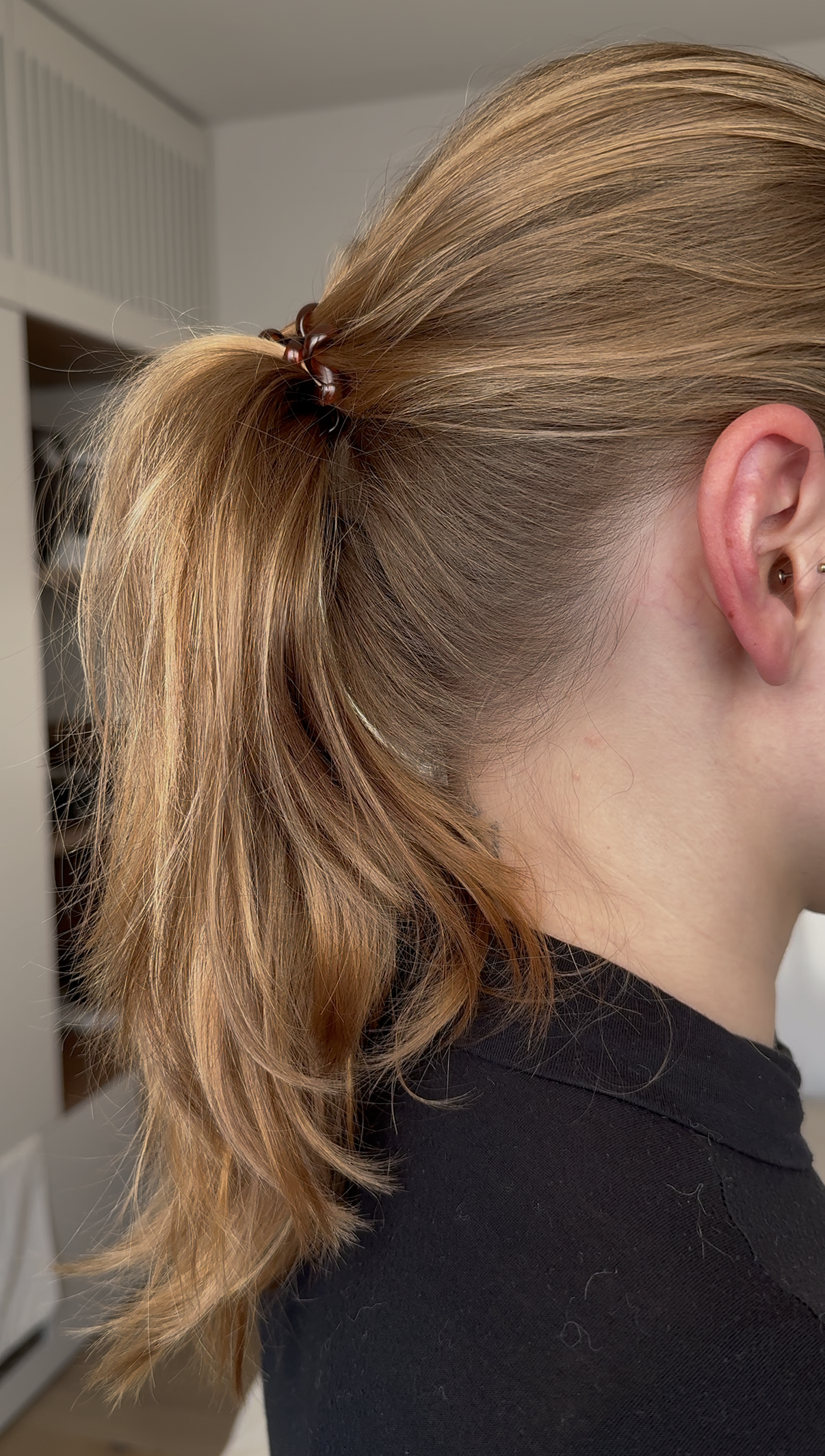 Eine Person mit blonden Haaren, die zu einem Pferdeschwanz gebunden sind 