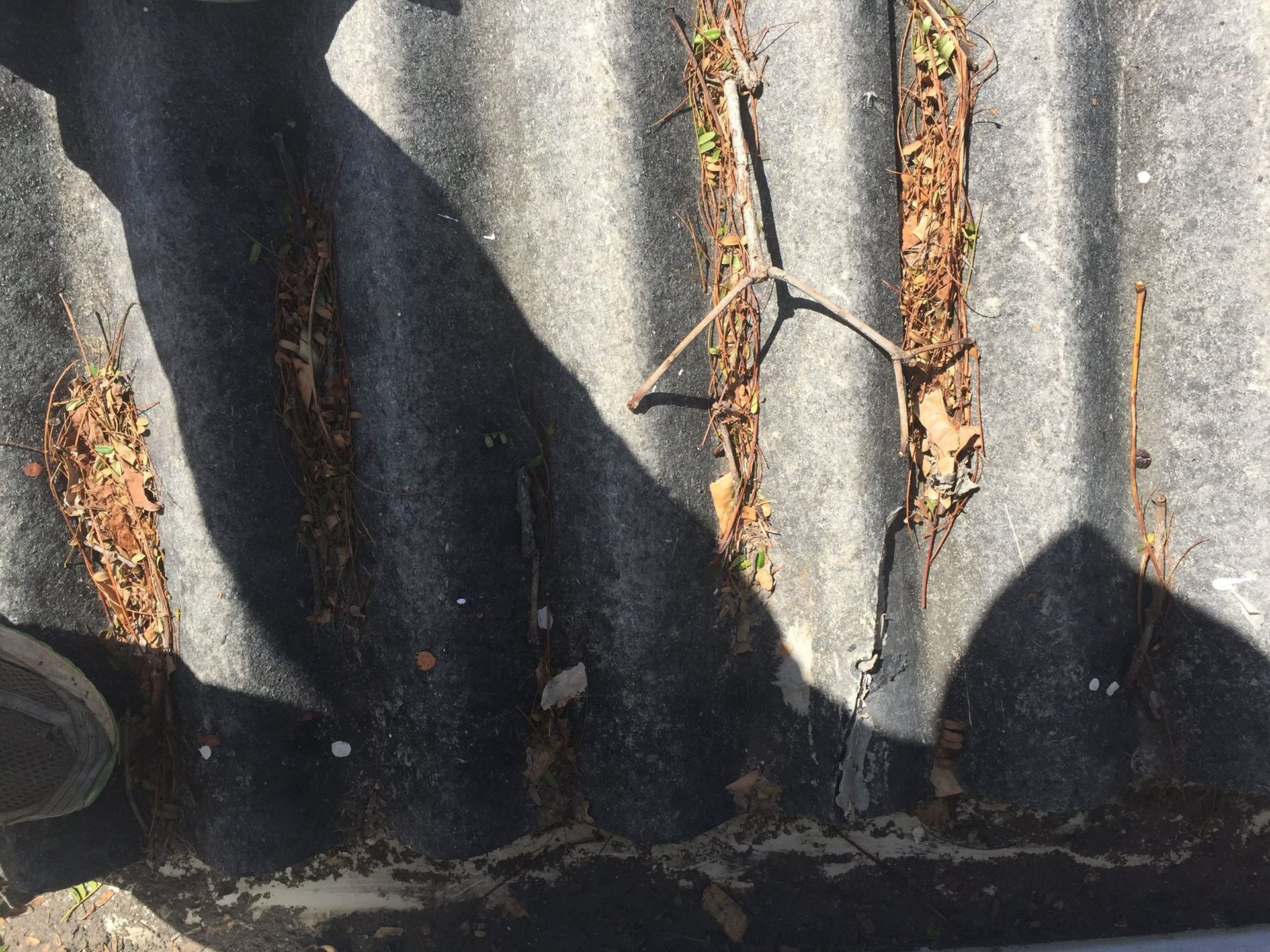 Dark corrugated roof with debris and shadows.