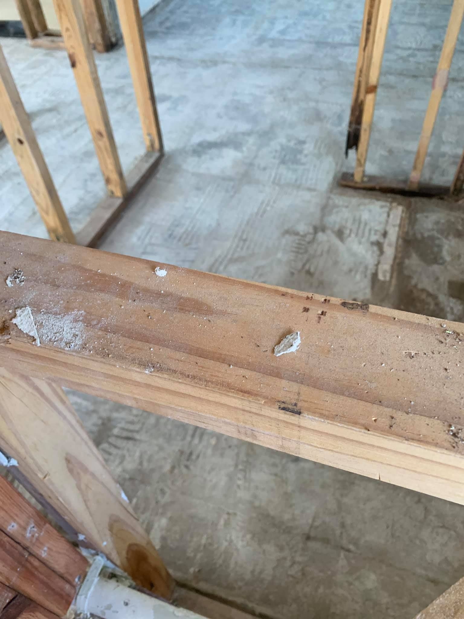 Wooden framing with white debris, concrete floor in unfinished construction.