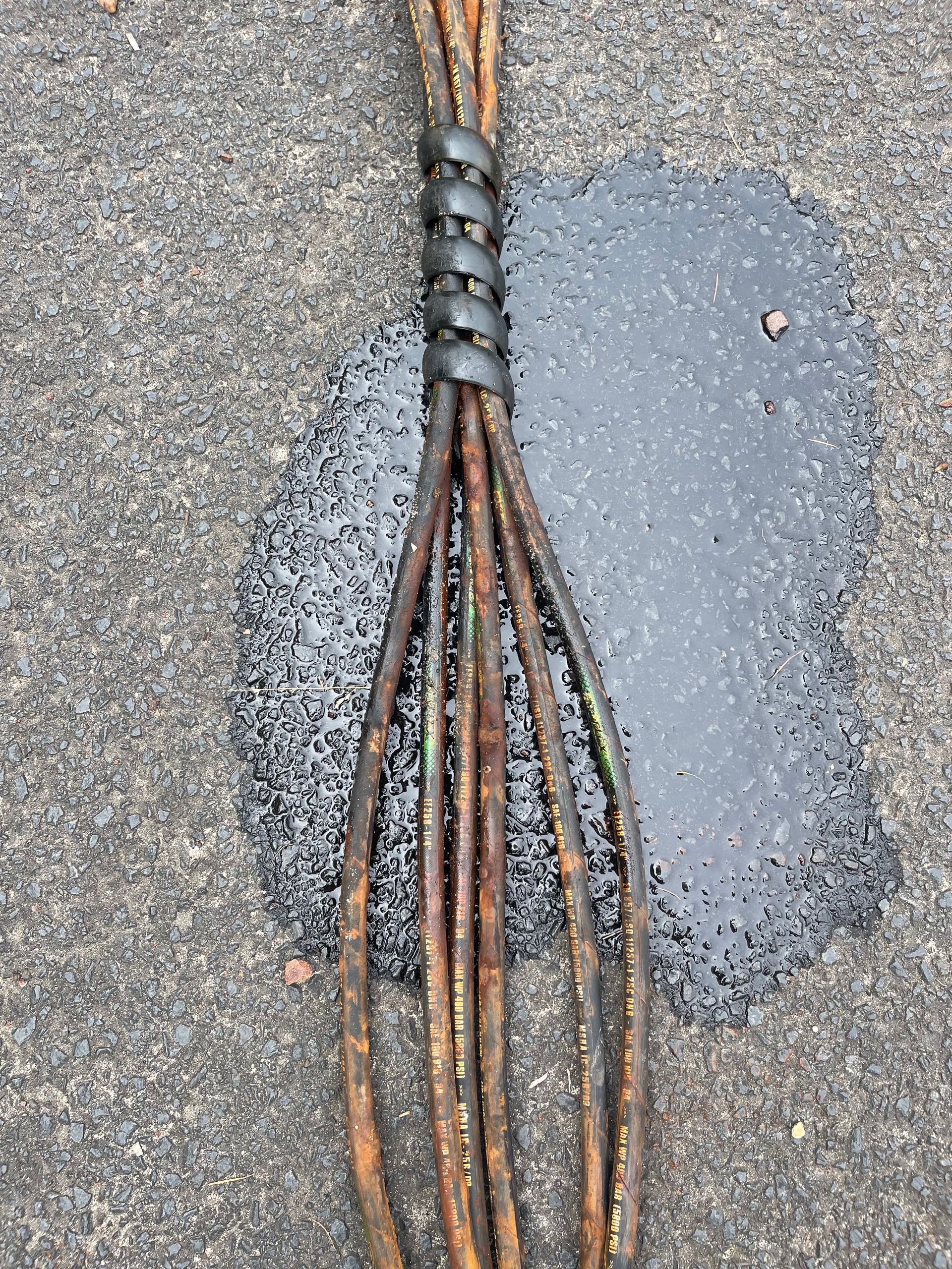 A wooden whisk is sitting on the ground next to a puddle of black liquid. — Hosemobile In Morisset, NSW
