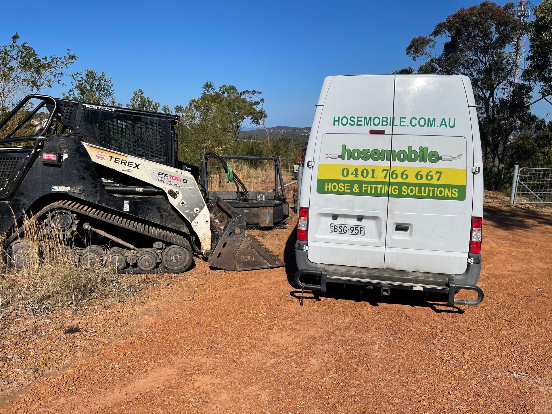 A white van is parked next to a bulldozer in a dirt field. — Hosemobile In Kariong, NSW
