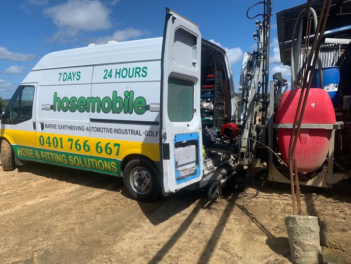 A white and yellow van with the door open is parked in the dirt. — Hosemobile In Kariong, NSW