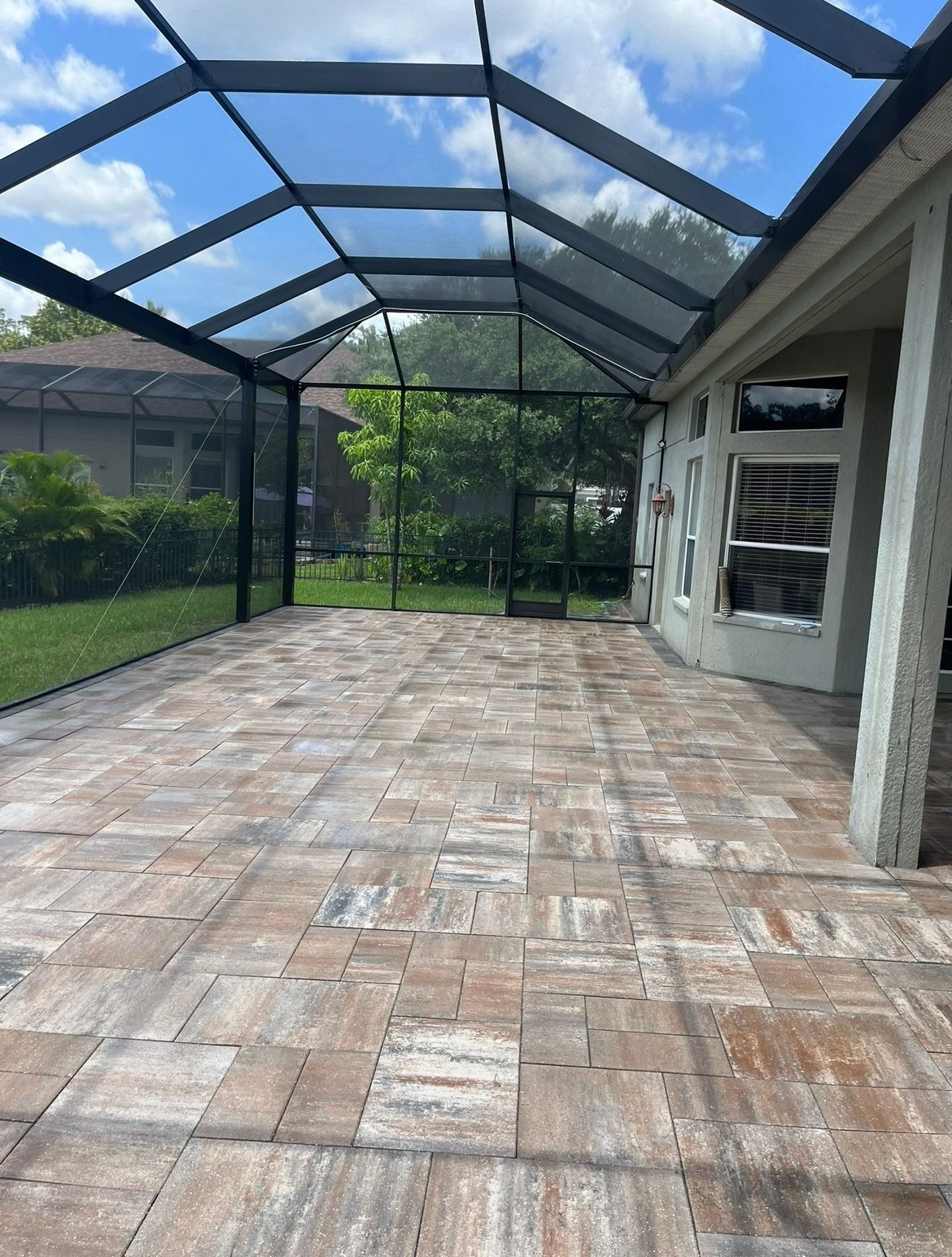 A large patio with a screened in porch and a clear roof.